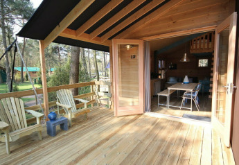 Véranda ouverte avec terrasse en bois et chaises, menant au Youpi! Lodge safari à Beerze Bulten, Pays-Bas.