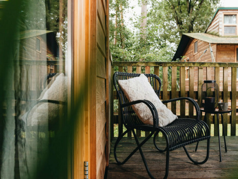 Udsigt til en hyggelig terrasse med sort stol, pude og bord på Youpi! Lodge, Beerze Bulten, Holland.