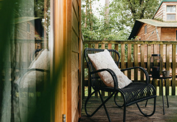 Veranda accogliente con sedia nera, cuscino e tavolino al Youpi! Lodge, Beerze Bulten, Paesi Bassi.