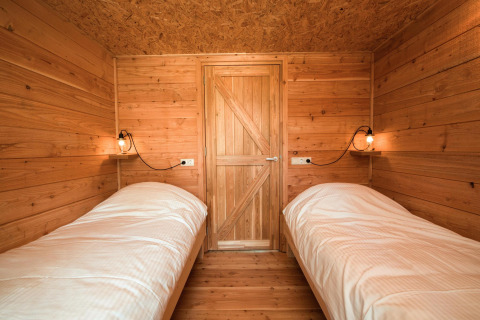 Dos camas individuales con sábanas blancas en un acogedor interior de madera en Youpi! Lodge, Beerze Bulten.