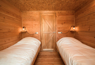 Dos camas individuales con sábanas blancas en un acogedor interior de madera en Youpi! Lodge, Beerze Bulten.