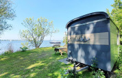 Klein blauw tiny house bij het meer met bomen en gras, Tiny Wagon bij Marina Parcs Almere, Nederland.