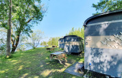 Pequeñas casas junto al lago en Marina Parcs Almere, Países Bajos, rodeadas de árboles y mesas de picnic.