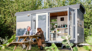 Deux personnes sont assises devant la Tiny Wagon à Marina Parcs Almere, aux Pays-Bas, profitant du plein air.