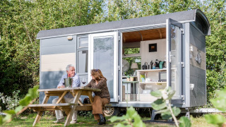 Dos personas sentadas fuera de la Tiny Wagon en Marina Parcs Almere, Países Bajos, disfrutando del día.