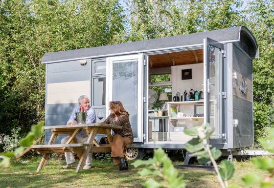 Due persone sedute fuori dalla Tiny Wagon al Marina Parcs Almere, Paesi Bassi, godendosi la natura.