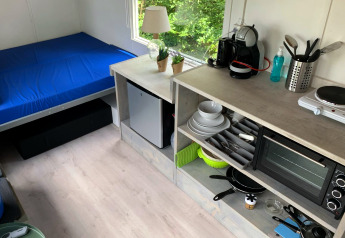 Interni compatti del Tiny Wagon a Marina Parcs Almere, Paesi Bassi, con letto e angolo cottura attrezzato.