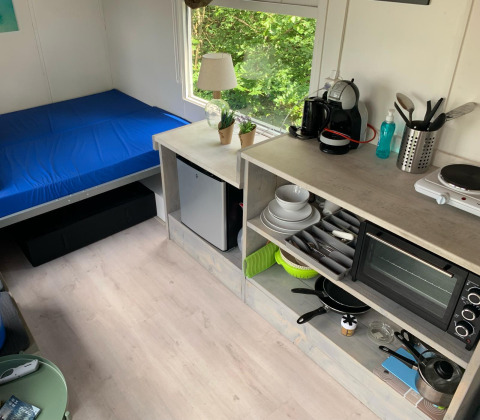 Interior compacto de Tiny Wagon en Marina Parcs Almere, Países Bajos, con cama y zona de cocina pequeña.
