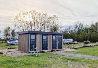 Kleines Haus namens Tiny Wagon bei Marina Parcs Almere, Niederlande, von Booten und Grün umgeben.
