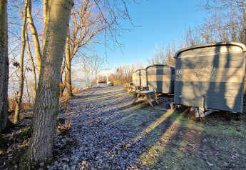 Kleine Häuser namens Tiny Wagon im Marina Parcs Almere, Niederlande, umgeben von Bäumen und Frost.