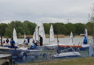 Piccole barche a vela e persone accanto a un lago al Tiny Wagon, Marina Parcs Almere, Paesi Bassi.