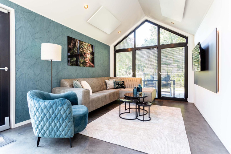 Modernes Tiny House-Wohnzimmer mit großen Fenstern, blauen Akzenten und stilvoller, gemütlicher Einrichtung.