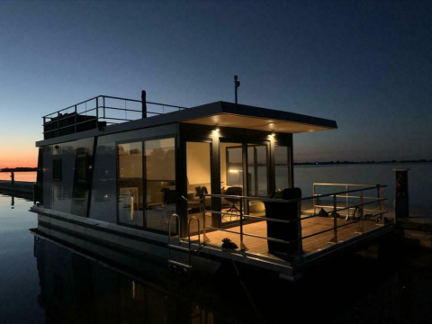 Péniche 'Earrebarre' à Welcome In - Friesland, Pays-Bas, éclairée au crépuscule sur l’eau calme.