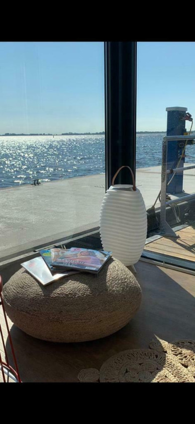 Sonnenlicht spiegelt sich auf dem Wasser bei Houseboat 'Earrebarre' mit Zeitschriften und Laterne, Friesland.