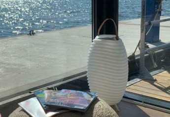 Sonnenlicht spiegelt sich auf dem Wasser bei Houseboat 'Earrebarre' mit Zeitschriften und Laterne, Friesland.