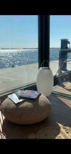 La luz del sol brilla en el agua desde Houseboat 'Earrebarre' con revistas y linterna en Welcome In, Frisia.