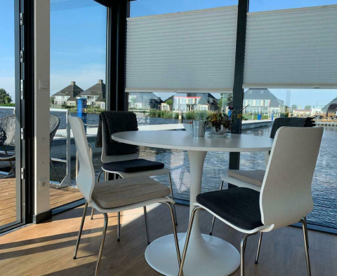 Mesa de comedor y sillas en la casa flotante 'Earrebarre' con vista al agua en Friesland, Países Bajos.