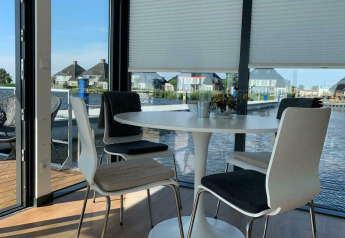 Tavolo da pranzo con sedie sulla houseboat 'Earrebarre' con vista sull'acqua in Friesland, Paesi Bassi.