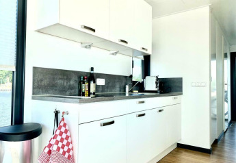 Cucina moderna sulla houseboat 'Earrebarre' con mobili bianchi e luce naturale a Friesland, Paesi Bassi.