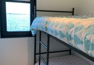Zimmer mit Etagenbetten und Blick auf das Wasser durch ein Fenster auf dem Hausboot 'Earrebarre' in Friesland, Niederlande.