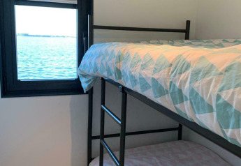 Zimmer mit Etagenbetten und Blick auf das Wasser durch ein Fenster auf dem Hausboot 'Earrebarre' in Friesland, Niederlande.