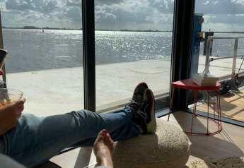 Vista rilassata da Houseboat 'Earrebarre' con i piedi in alto, sul lago e le nuvole a Friesland, Paesi Bassi.