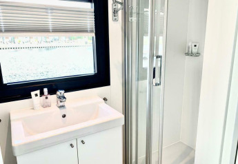 Bagno luminoso sulla houseboat 'Earrebarre' con lavabo bianco, finestra e doccia a Friesland, Paesi Bassi.