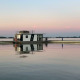 Houseboat 'Earrebarre' floating on peaceful water at dusk in Friesland, Netherlands, with calm reflections.