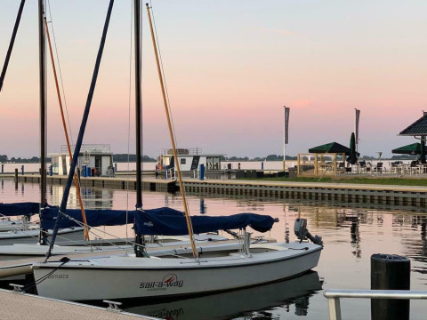 Veleros amarrados al atardecer junto a la casa flotante 'Earrebarre' en Welcome In - Friesland, Países Bajos.