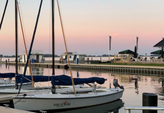 Veleros amarrados al atardecer junto a la casa flotante 'Earrebarre' en Welcome In - Friesland, Países Bajos.
