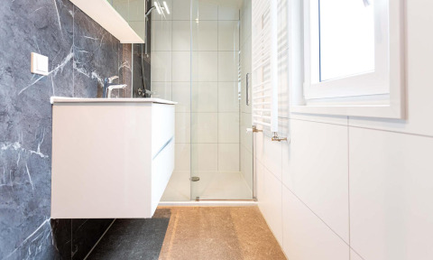 Baño moderno con lavabo flotante, ducha sin bordes y ventana grande en Silva Wellness, Landgoed de Scheleberg.