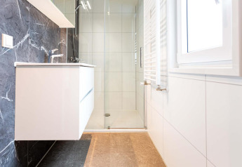 Baño moderno con lavabo flotante, ducha sin bordes y ventana grande en Silva Wellness, Landgoed de Scheleberg.