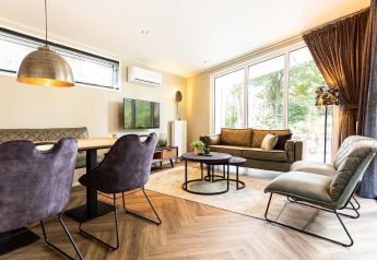 Moderne woonkamer in Silva Wellness Lodge op Landgoed de Scheleberg, Nederland, met grote ramen en stijlvolle inrichting.