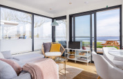 Bright modern houseboat interior with large windows, water view, cozy seating area at Friesland, Netherlands.
