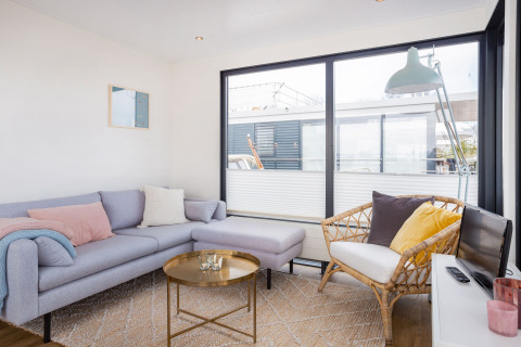 Soggiorno luminoso su Houseboat Aqua Dolce a Friesland, Paesi Bassi, con divano moderno e ampie finestre.