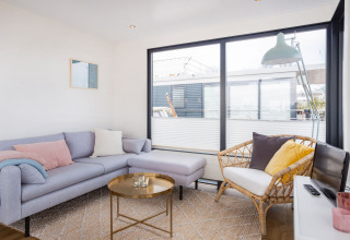 Soggiorno luminoso su Houseboat Aqua Dolce a Friesland, Paesi Bassi, con divano moderno e ampie finestre.