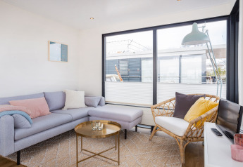 Soggiorno luminoso su Houseboat Aqua Dolce a Friesland, Paesi Bassi, con divano moderno e ampie finestre.