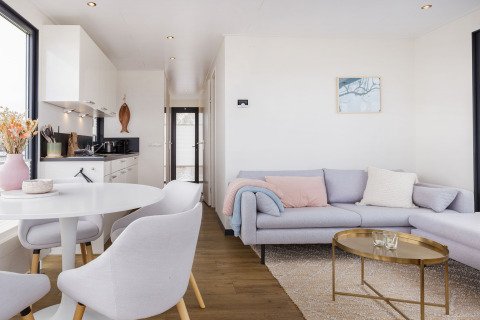 Intérieur lumineux et moderne d’une péniche avec cuisine, salle à manger et salon à Houseboat Aqua Dolce, Friesland.