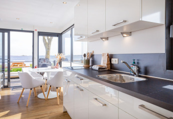 Cucina moderna luminosa e zona pranzo su Houseboat Aqua Dolce con vista sull’acqua in Frisia, Paesi Bassi.