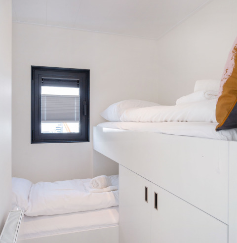 Cabina moderna con letti a castello bianchi e finestra su Houseboat Aqua Dolce, Friesland, Paesi Bassi.