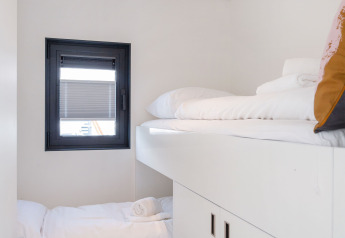 Cabina moderna con letti a castello bianchi e finestra su Houseboat Aqua Dolce, Friesland, Paesi Bassi.