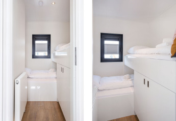 Zona notte moderna con letti a castello su Houseboat Aqua Dolce a Welcome In - Friesland, Paesi Bassi, arredo bianco.