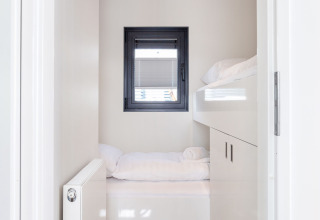 Lichte, moderne slaapkamer met raam en stapelbedden in Houseboat Aqua Dolce, Friesland, Nederland.