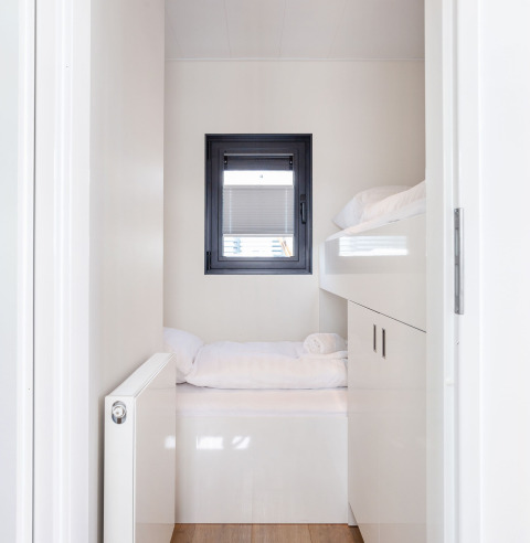 Lichte, moderne slaapkamer met raam en stapelbedden in Houseboat Aqua Dolce, Friesland, Nederland.