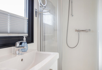 Salle de bain moderne sur la Houseboat Aqua Dolce en Frise, Pays-Bas, avec douche, lavabo et fenêtre.