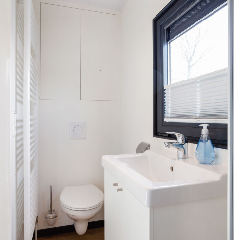 Baño blanco moderno en Houseboat Aqua Dolce con inodoro suspendido, lavabo y ventana en Friesland, Países Bajos.