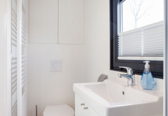 Baño blanco moderno en Houseboat Aqua Dolce con inodoro suspendido, lavabo y ventana en Friesland, Países Bajos.