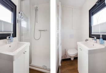 Baño moderno en la casa flotante Aqua Dolce en Friesland, Países Bajos, con ducha, lavabo y WC.