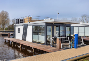Moderna houseboat Aqua Dolce a Welcome In - Friesland, Paesi Bassi, ormeggiata su un molo di legno.