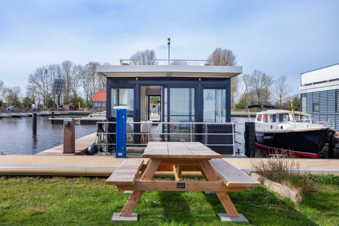 Hausboot Aqua Dolce bei Welcome In - Friesland, Niederlande, mit Picknicktisch und Hafenblick.